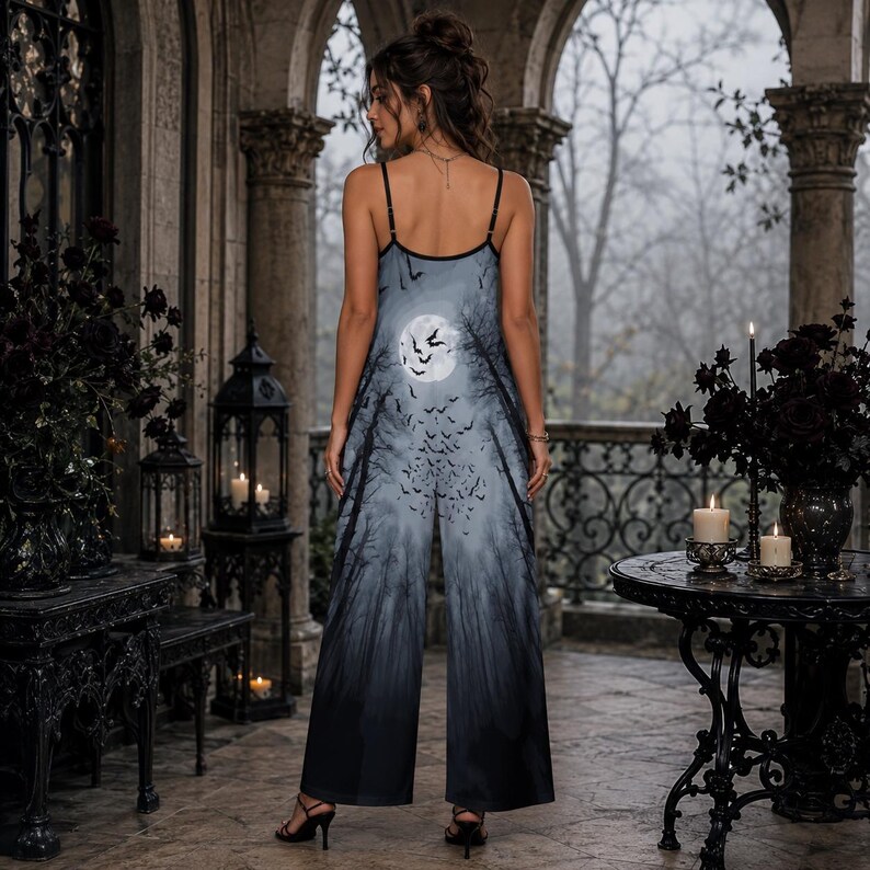 May include: A sleeveless jumpsuit featuring a full moon and a flock of bats flying over a dark, silhouetted forest print. The garment has thin spaghetti straps, a scoop neckline, and wide-leg trousers that transition from a light gray to black.