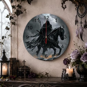 May include: A round wall clock featuring a dark, atmospheric illustration of a hooded figure in a cloak riding a black horse while holding a staff. The clock face displays black Arabic numerals from 1 to 12 and has black hour and minute hands.