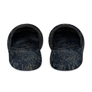 May include: A pair of slip-on slippers featuring a dark navy blue and charcoal gray botanical pattern with intricate illustrations of branches, leaves, and berries. The interior lining is a solid dark gray, and the rounded toe design provides a wide opening for easy entry, showcasing a consistent dark color palette throughout the fabric.