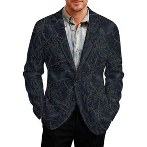 Pode incluir: Um blazer azul-marinho escuro com um padr&atilde;o repetitivo de p&aacute;ssaros pretos pousados em galhos de &aacute;rvores entrela&ccedil;ados com folhas. O blazer tem lapela entalhada, dois bot&otilde;es frontais e &eacute; usado sobre uma camisa jeans azul-clara.
