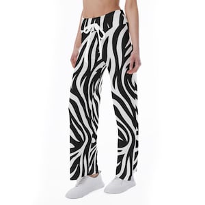 May include: Black and white zebra print pants with a drawstring waist. The pants have a wide leg design and are made of a lightweight material. The zebra pattern is bold and eye-catching, creating a striking visual effect.