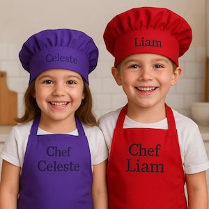 May include: Two children wearing personalized chef hats and aprons. The purple hat says "Celeste" and the red hat says "Liam". The aprons are embroidered with "Chef Celeste" and "Chef Liam".
