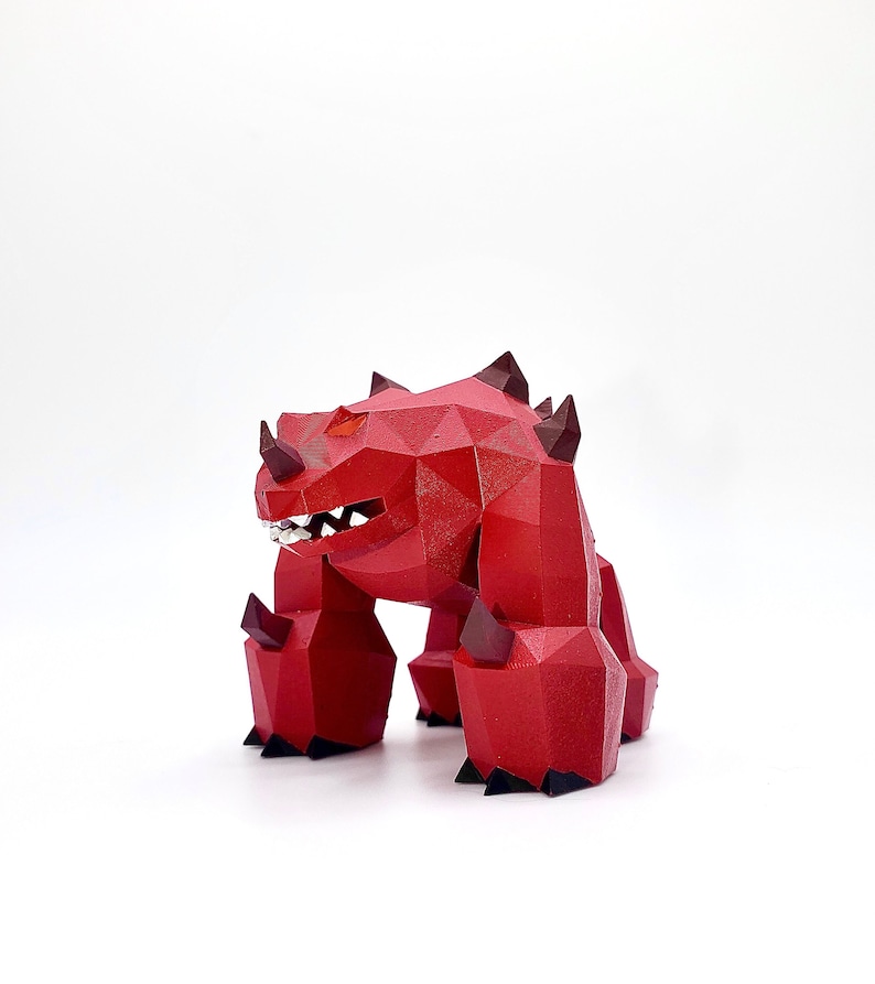 May include: A red, polygonal monster figurine with black claws and horns. The monster has a wide open mouth with teeth.