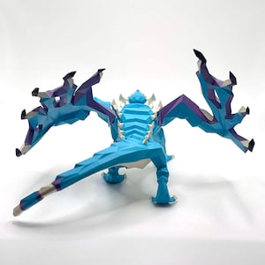 May include: A low-poly style dragon figurine in shades of blue, purple, and white. The dragon is posed with its wings spread, showcasing a geometric design. The figurine has a detailed spine and sharp claws.