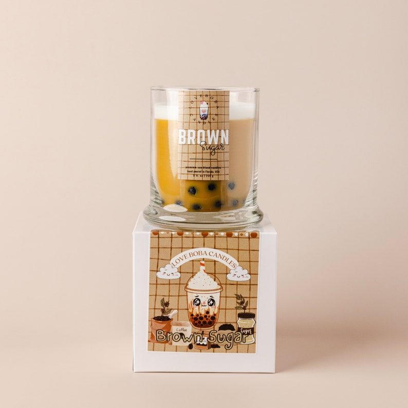 May include: A brown sugar boba candle in a clear glass jar with a white lid. The jar is sitting on a white box with a brown and white checkered pattern. The box has the text "I Love Boba Candles" and "Brown Sugar" on it. The candle has a brown sugar scent and is decorated with boba pearls.