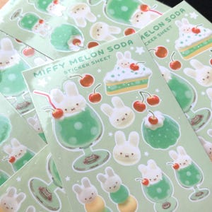 May include: Sheets of stickers featuring a cute bunny character and the text "Miffy Melon Soda." The stickers depict the bunny in a green soda drink, on a cake, and as a bunny head. Cherries and stars are also included in the design.