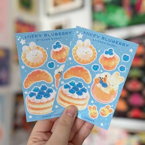 May include: Two sticker sheets with a light blue background featuring illustrations of food items and a bunny character. The text "MIFFY BLUBERRY STICKER SHEET" is printed at the top. The stickers include pancakes, croissants, and cupcakes.