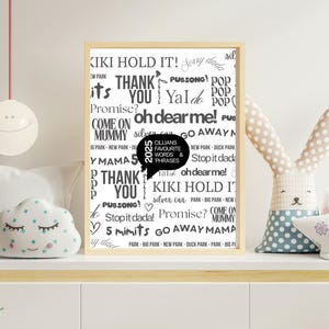 May include: A framed print with a light wood frame featuring a collection of words and phrases in black font. A speech bubble contains the text "Cillians Favourite Words & Phrases". The print is displayed on a white surface with decorative items.