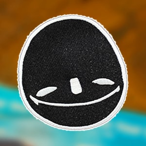 May include: Black embroidered patch with a white smiling face. The face has two small eyes and a wide mouth.