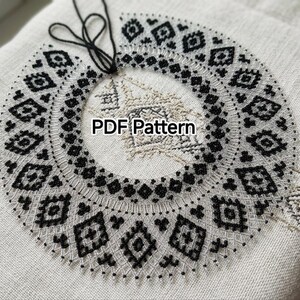 Könnte beinhalten: Ein kreisförmiger Kragen mit aufwendigen schwarzen Perlenstickereien in einem geometrischen Rautenmuster auf hellem Stoff. Das Design umfasst eine zentrale Schlaufe aus schwarzem Faden und den Text PDF Pattern in der Mitte des kreisförmigen Stücks.