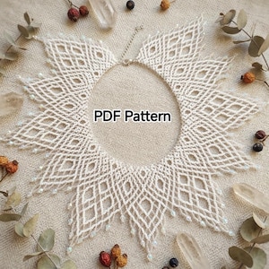 Könnte beinhalten: Eine weiße Perlenkette mit einem komplexen, durchbrochenen Rautenmuster, zarten Fransenrändern und einer metallischen Kettenverlängerung. Der Text PDF Pattern ist in der Mitte des kreisförmigen Perlendesigns zentriert.