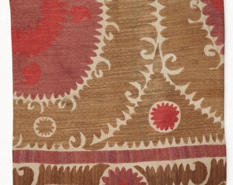 May include: A square, decorative pillow with a brown, red, and cream pattern. The pillow features a central brown field with cream-colored, stylized floral and scroll designs. The top left corner is a deep red, transitioning to a lighter red. The bottom has a red border.