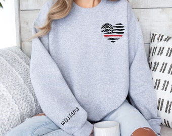 May include: A gray sweatshirt with a black and red heart-shaped American flag design on the front. The text "8.11.11" is embroidered on the left sleeve.