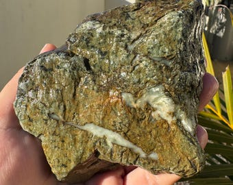 May include: A large, rough, green and white rock with a smooth, polished surface. The rock has a natural, organic look and feel.