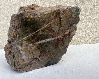 May include: A large, irregularly shaped rock with a green, brown, and white marbled pattern. The rock has a rough, textured surface.