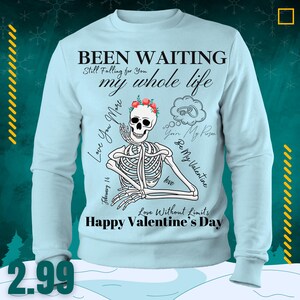 Op de afbeelding: Lichtblauw sweatshirt met een skeletafbeelding met een bloemenkrans. Tekst bevat "Been Waiting", "my whole life" en "Happy Valentine's Day". Het ontwerp heeft een Valentijnsdagthema.