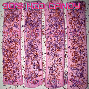May include: Four pink candy bars covered in red and purple sprinkles. The candy bars are labeled "90's Kid Candy".