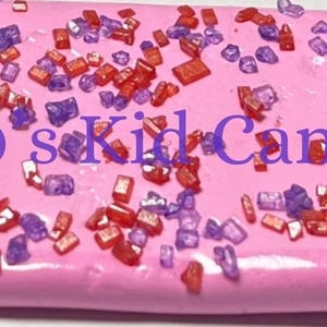 May include: Pink candy bar with red and purple sprinkles. The text "90's Kid Candy" is printed on the candy bar.