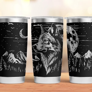 May include: Three stainless steel tumblers with a black and white design of a wolf howling at the moon in a forest setting. The design includes mountains and trees.