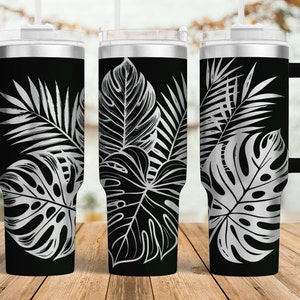 May include: Three stainless steel tumblers with a black background and a silver tropical leaf design.