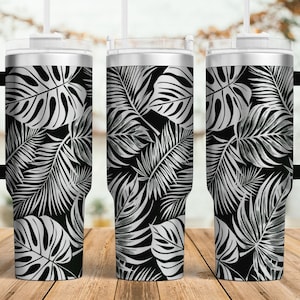 May include: Three stainless steel tumblers with black and white tropical leaf designs. The tumblers have lids and straws.