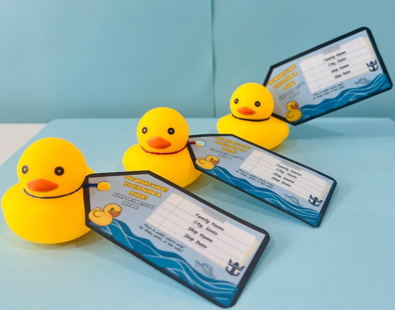 May include: Yellow rubber duck toys with orange beaks and black eyes, each attached to a tag. The tags have a blue wave design and text that reads "Oh What Luck! You Found a Duck!" and space for information.