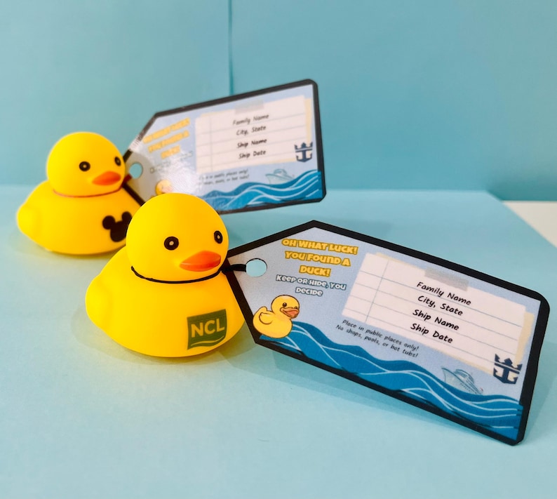 May include: Two yellow rubber duck toys with orange beaks and black eyes are next to two luggage tags. One duck has a Mickey Mouse logo, the other has an NCL logo. The tags have text that reads "OH WHAT LUCK! YOU FOUND A DUCK!" and space for personal information.