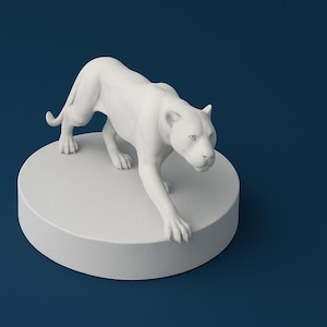 May include: White ceramic figurine of a crouching panther. The panther is posed with its head lowered and its front paw extended. The figurine is on a white circular base.