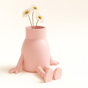 Peut inclure: Un vase en céramique rose clair avec des bras et des jambes, ressemblant à une figurine assise. Le vase contient plusieurs marguerites blanches avec des centres jaunes. Le design est ludique et unique, adapté à la décoration intérieure.