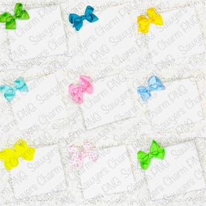 May include: Eight blank white cards with different colored bows on top of a white lace background. The bows are green, blue, yellow, pink, light pink, and light blue.
