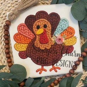May include: A white canvas with a colorful turkey design. The turkey features a knitted texture in shades of brown, orange, yellow, and blue. The text "Always Charm PNG DESIGNS" is printed on the canvas.