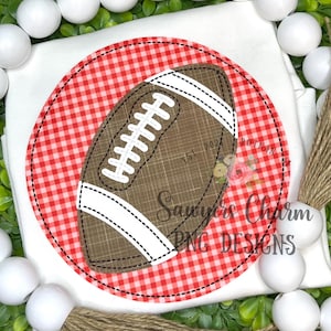 Puede incluir: Una camiseta blanca con un diseño de fútbol americano. El balón es marrón con rayas y costuras blancas, sobre un círculo de cuadros rojos y blancos. El texto "Sawyers Charm PNG Designs" es visible.