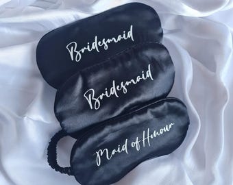 Puede incluir: Tres antifaces de satén negro con letras blancas en cursiva. Dos antifaces llevan la palabra Bridesmaid y uno lleva el texto Maid of Honour. Cada antifaz tiene un acabado suave y brillante con una banda elástica negra para ajustar a la cabeza.