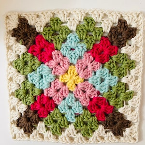 May include: A crocheted granny square with a colorful geometric pattern. The center of the square is yellow, surrounded by pink, blue, green, and brown.