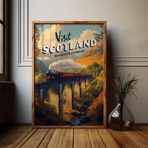 Può includere: Un poster di viaggio vintage incorniciato con le parole "Visit Scotland" e "Hogwarts Express". Il poster raffigura un treno che attraversa un ponte di pietra su un fiume, con montagne e fogliame autunnale sullo sfondo. La cornice è in legno.