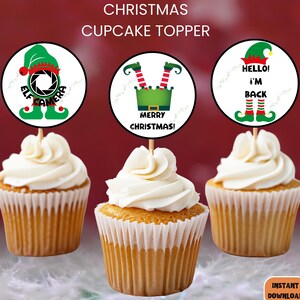 Puede incluir: Tres adornos para cupcakes de Navidad con un elfo con una cámara, un elfo con las piernas en el aire y un elfo con el texto "Hello! I'm Back".