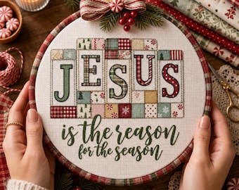 May include: A circular embroidery hoop containing a cross-stitch project on white fabric. The design features the word JESUS in large, patchwork-style letters, with the text is the reason for the season below. A red and white bow sits on top.
