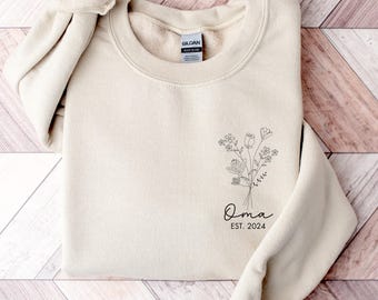 May include: A beige sweatshirt with a floral design and the text "Oma Est. 2024" printed on the front.