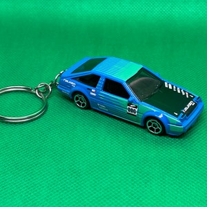 May include: A blue and black toy car keychain with the word "FALKEN" on the side and the number "886" on the windshield.