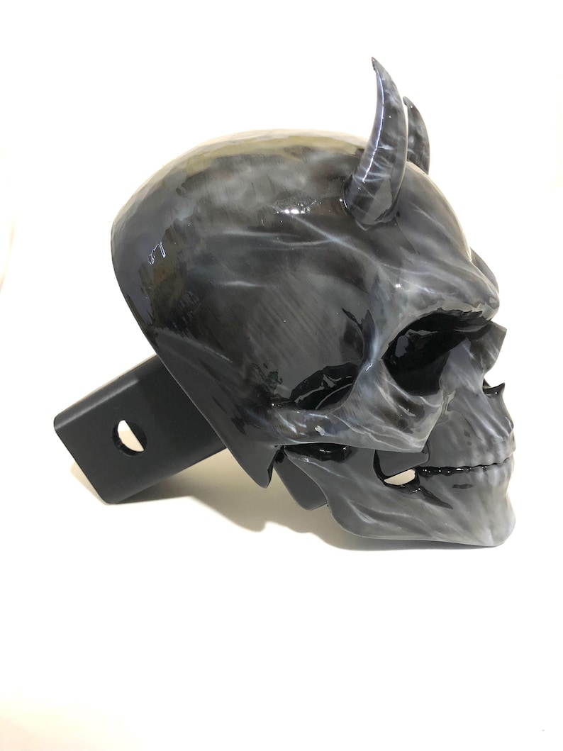 May include: A black and white skull hitch cover with horns. The skull has a detailed design and a glossy finish.