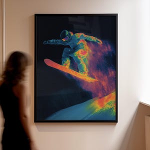 May include: A framed print depicting a snowboarder in action, with a dark background and a burst of colourful energy. The snowboarder is captured mid-air, with the artwork's vibrant colours emphasising the dynamic movement.