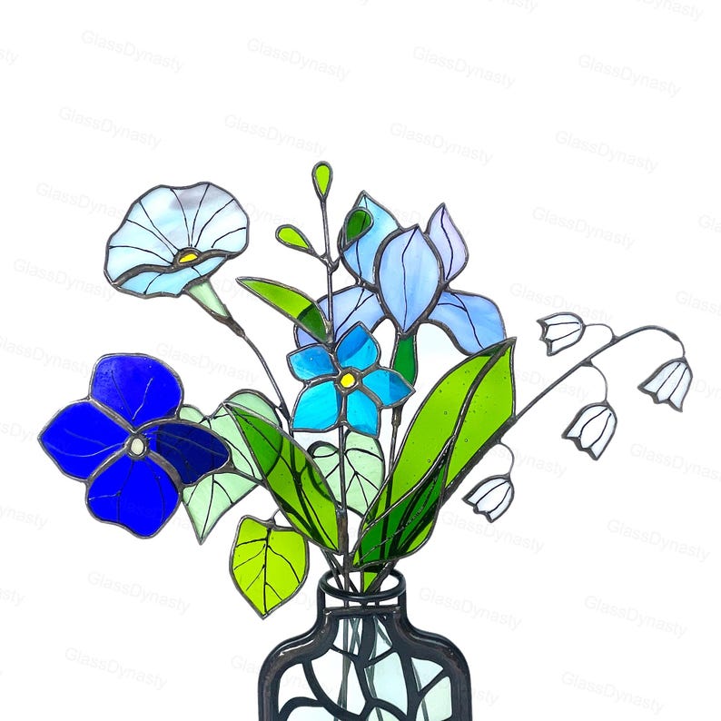 May include: A stained glass bouquet featuring blue and white flowers, green leaves, and white lily of the valley blooms. The flowers are arranged in a black vase. The image is set against a white background.