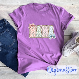 Könnte beinhalten: Ein lilafarbenes T-Shirt mit dem Wort "MAMA" in einem farbenfrohen, gemusterten Design. Die Buchstaben sind mit einem Leopardenmuster umrandet, mit rosa, grünen und blauen Akzenten. Das Shirt wird mit blauen Jeans und weißen Turnschuhen gezeigt.