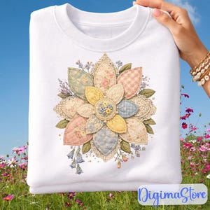 Puede incluir: Sudadera blanca con un diseño floral. El diseño es una flor de patchwork con pétalos de colores pastel, detalles de encaje y un grupo central de pequeñas cuentas. El fondo es un campo de flores bajo un cielo azul.