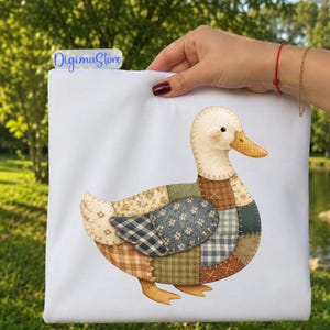 May include: A white fabric item featuring a graphic of a duck composed of various patchwork patterns in shades of blue, green, brown, and cream. The duck has a yellow beak and a stitched appearance. The text DigimaStore is visible in the corner.