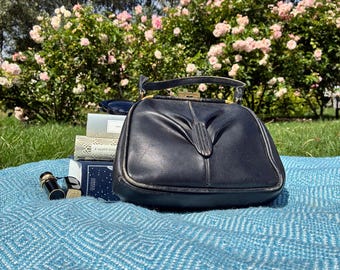 Bolso vintage de piel negra con cierre de boquilla y herrajes de latón: un bolso clásico de mediados de siglo.