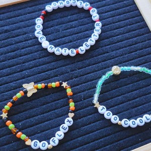 May include: Three beaded bracelets with different colored beads and words spelled out on the beads. The bracelets say "Love Hate Letter To", "Go Flex", and "Too Cool To Die".