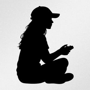 May include: A black silhouette of a person with long hair wearing a baseball cap, sitting in a cross-legged position while holding a video game controller. The figure is depicted in profile, showing the outline of the head, torso, and legs.