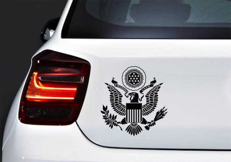 Pode incluir: Adesivo de vinil preto e branco do Grande Selo dos Estados Unidos, apresentando uma &aacute;guia com as asas abertas, um escudo com listras verticais e as palavras "E Pluribus Unum".