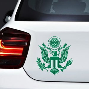 Pode incluir: Adesivo de vinil verde do Grande Selo dos Estados Unidos, apresentando uma &aacute;guia com as asas abertas, um escudo com listras verticais, um ramo de oliveira e flechas. O texto "E PLURIBUS UNUM" &eacute; exibido acima da &aacute;guia.